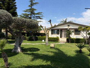 Uma casa com gramado bem cuidado, uma árvore grande e uma antena parabólica.