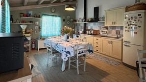 Een keuken met houten balken, een eettafel voor vier personen en een koelkast met magneetjes.