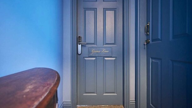 A closed door with a nameplate reading 'Gains Law' and a keyhole.