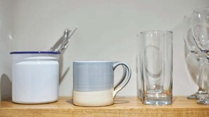 A kitchen counter with a white mug, a blue and white mug, and a clear glass pitcher.