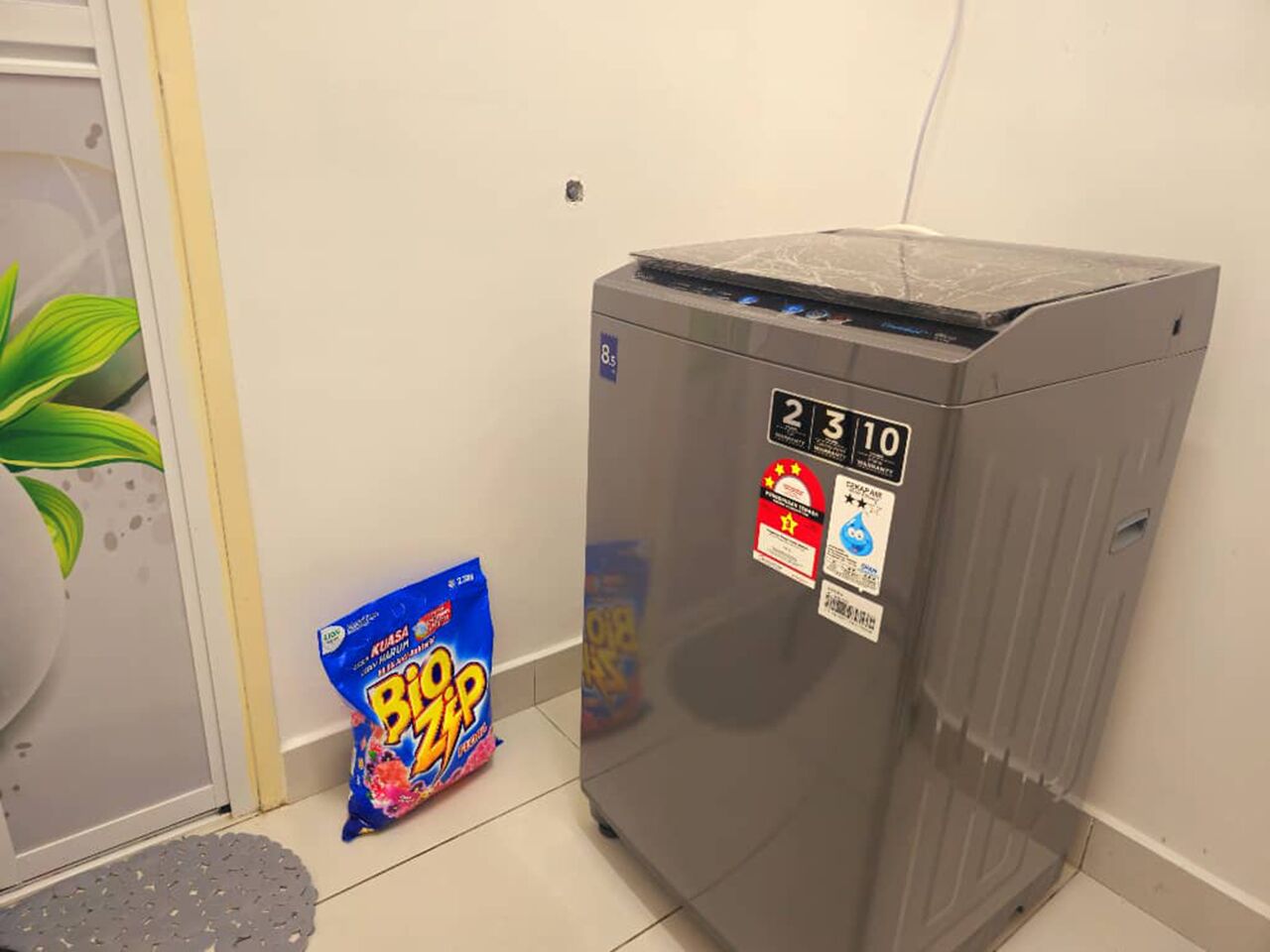 A compact, metallic vending machine with a digital display, a blue bag of BIPOP chips, and a potted plant.