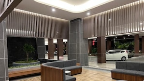 Eine moderne Lobby mit Sitzbereichen, einer Rezeption und einem Parkplatz.