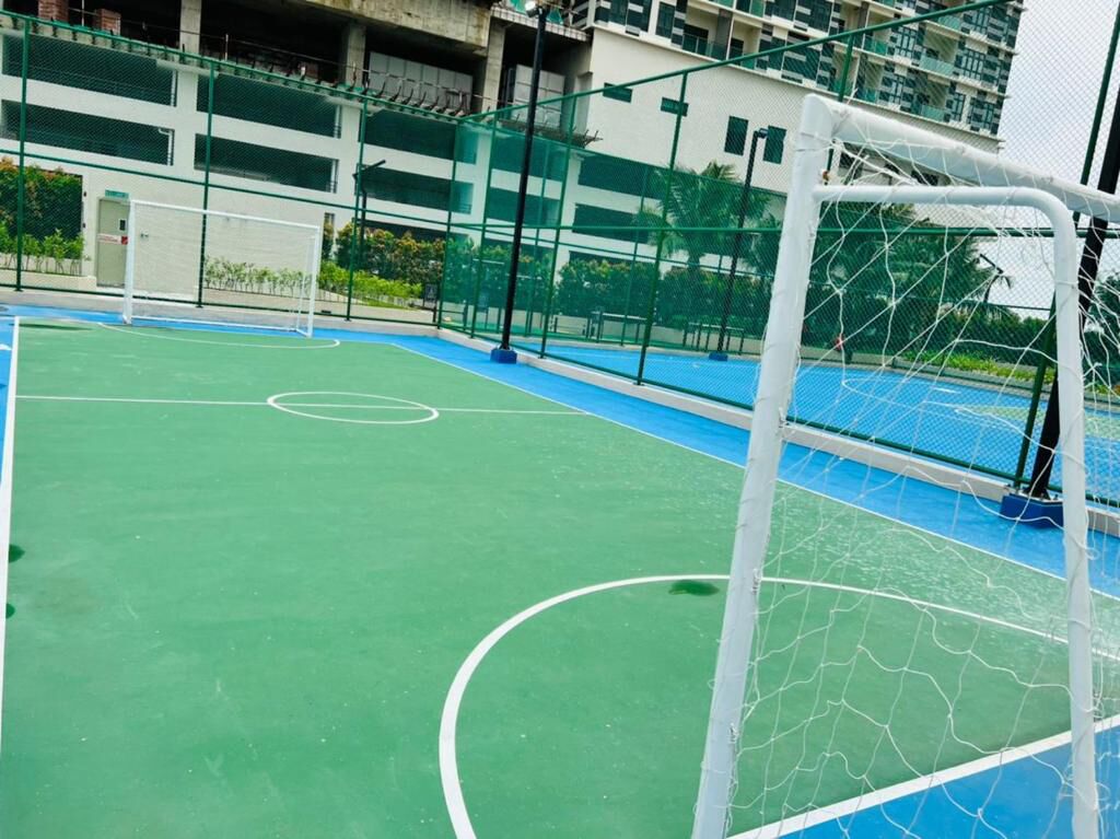 A sports court with a goalpost, surrounded by a fence and buildings in the background.