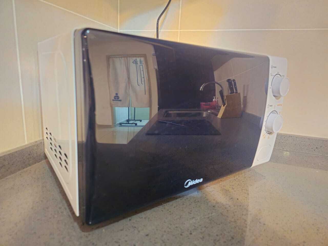 Un four à micro-ondes noir et blanc posé sur un plan de travail de cuisine.