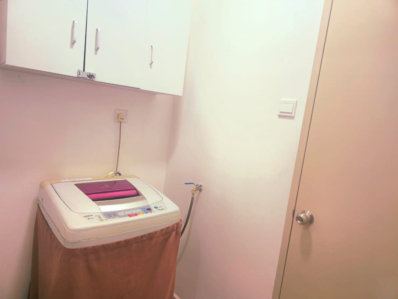 A small room with a white cabinet, a medical device on a table, and a door.