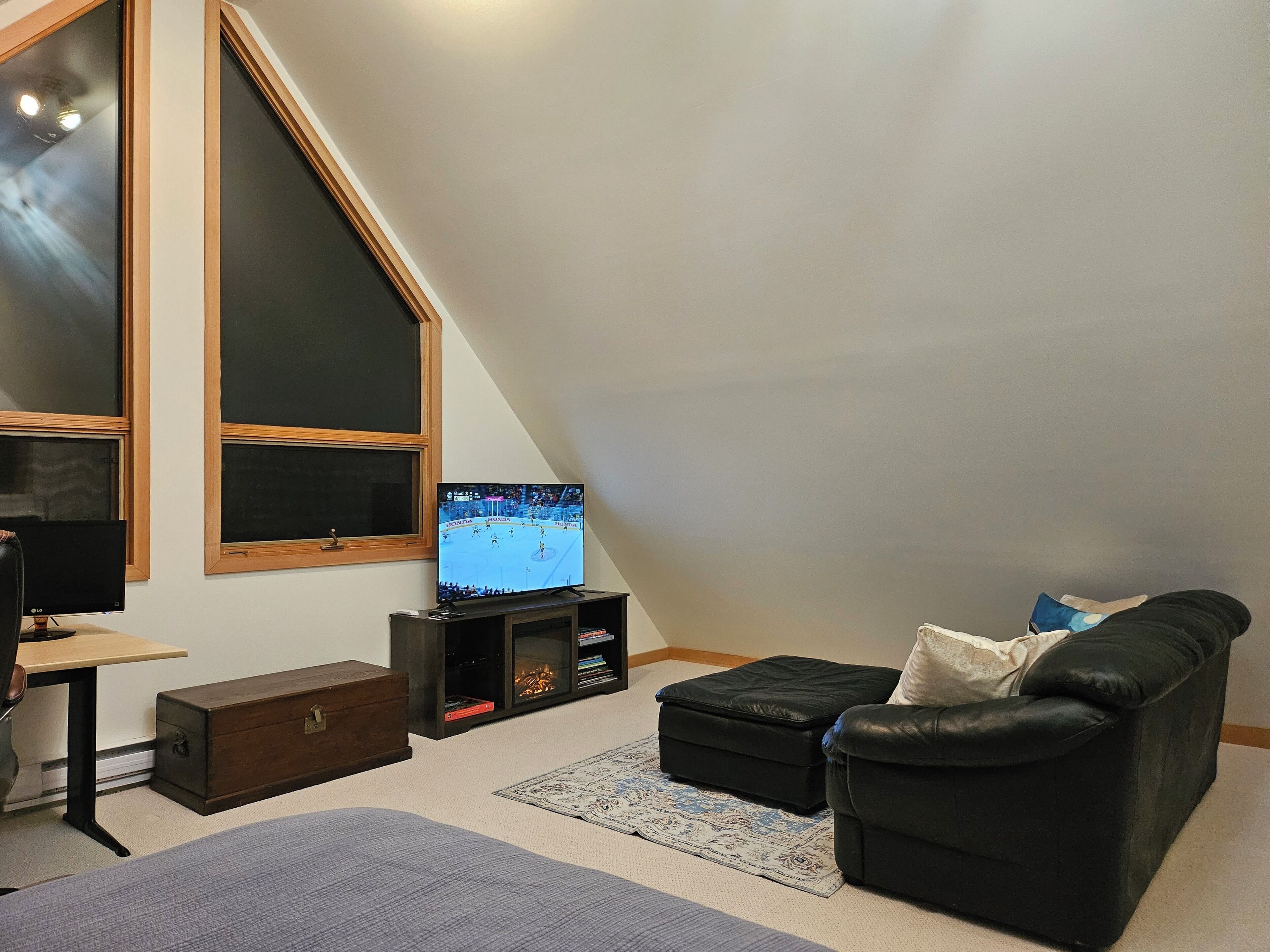 Un salon avec une télévision, un canapé, un bureau et une fenêtre.