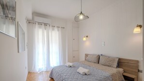 Ein Schlafzimmer mit einem Bett, einem Holzkopfende, einer Pendelleuchte und einem Fenster mit Vorhängen.