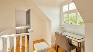 A room with a desk, chair, and a window with a view of greenery.