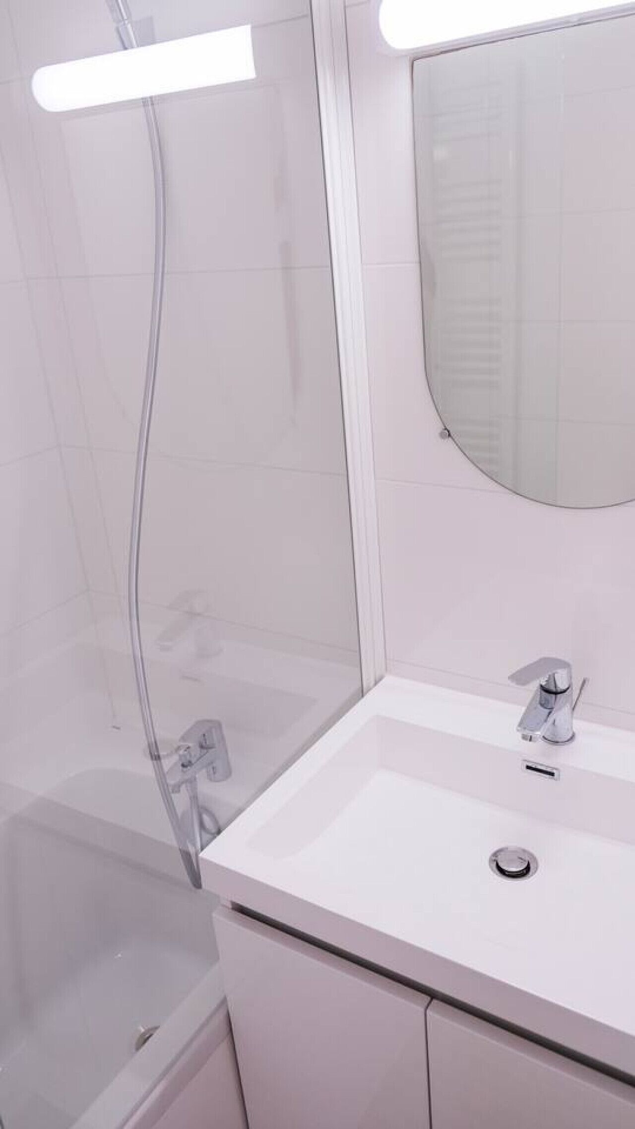 Une salle de bain avec une douche à parois de verre, un lavabo blanc et un miroir.