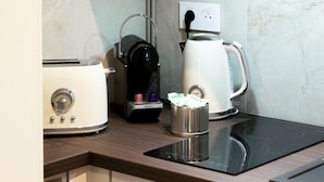 A kitchen with a toaster, coffee maker, kettle, and a power outlet on the wall. - Trendy studio apartment, 2 minutes from the very center of town (Caen)