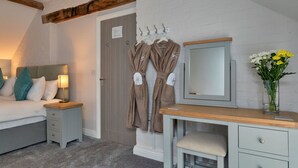 Ein Schlafzimmer mit Bett, Nachttisch, Kleiderhaken und Spiegel.