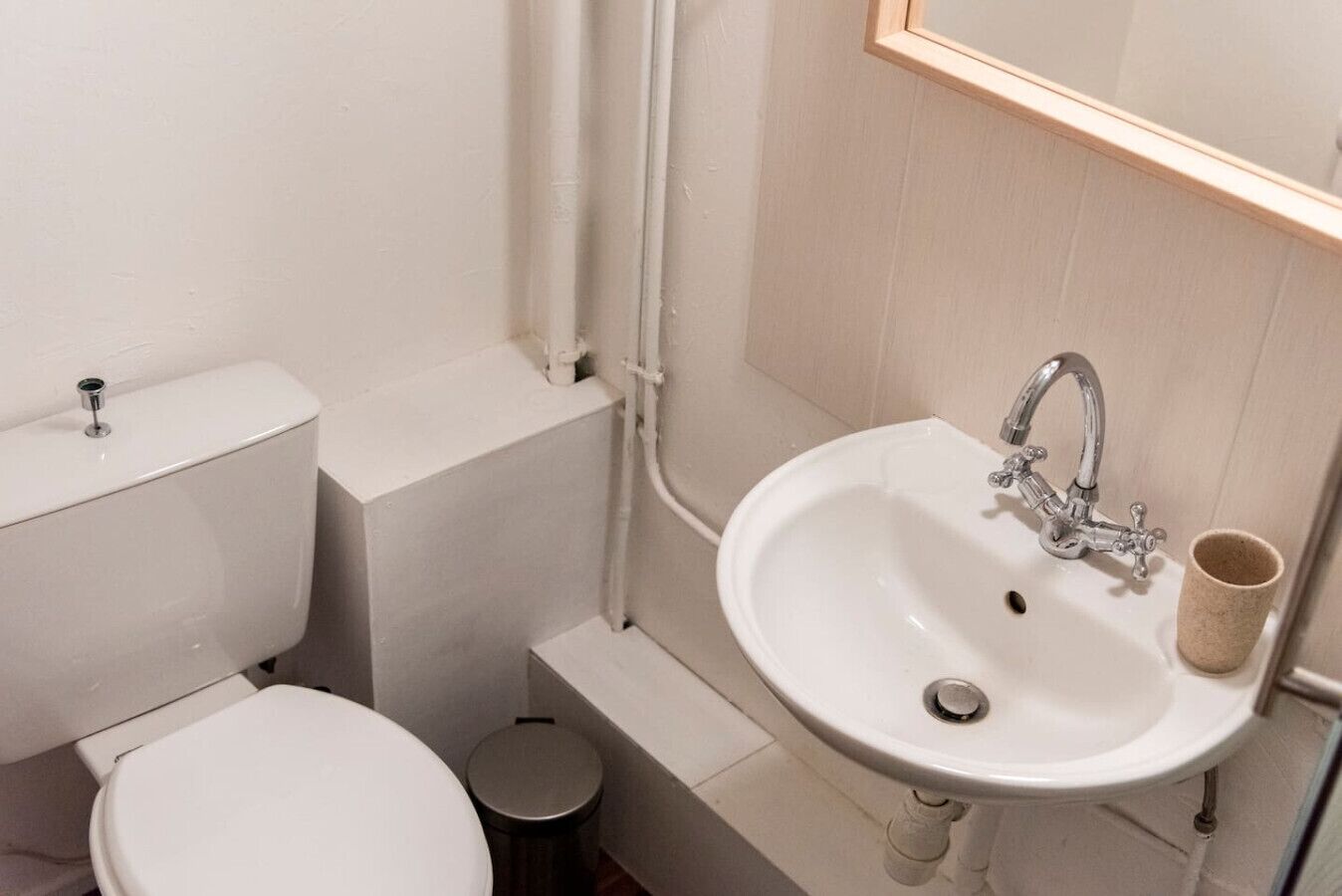 Een kleine, schone badkamer met toilet, wastafel en een spiegel boven de wastafel.