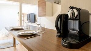 A kitchen with a coffee maker, a dining table set with plates, glasses, and cutlery. - Studio with free, private parking (Caen)