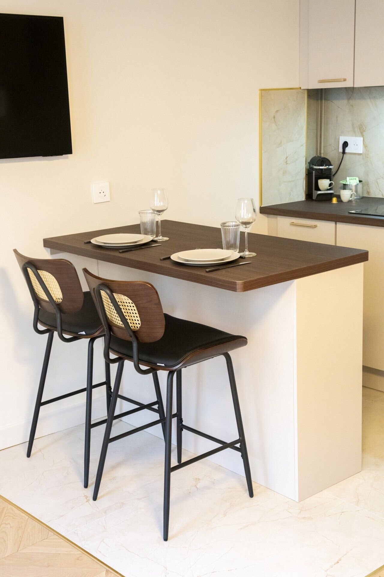 A small kitchen with a dining area, including a table set with plates, glasses, and cutlery.
