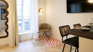Un comedor con una mesa dispuesta para dos personas, una silla, una mesa redonda de vidrio y una alfombra estampada.