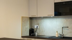 Una cocina moderna con salpicadero de mármol, estufa integrada y una zona de bar con taburetes.