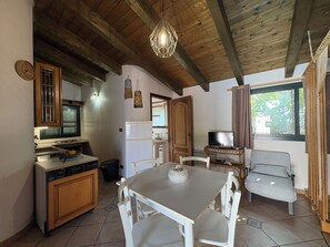 A compact kitchen with a dining area, wooden ceiling beams, a television, and a window with curtains. - Wonderful  villa for 5 guests with WIFI, A/C, pool, TV, patio and panoramic view (Chiaramonte Gulfi)