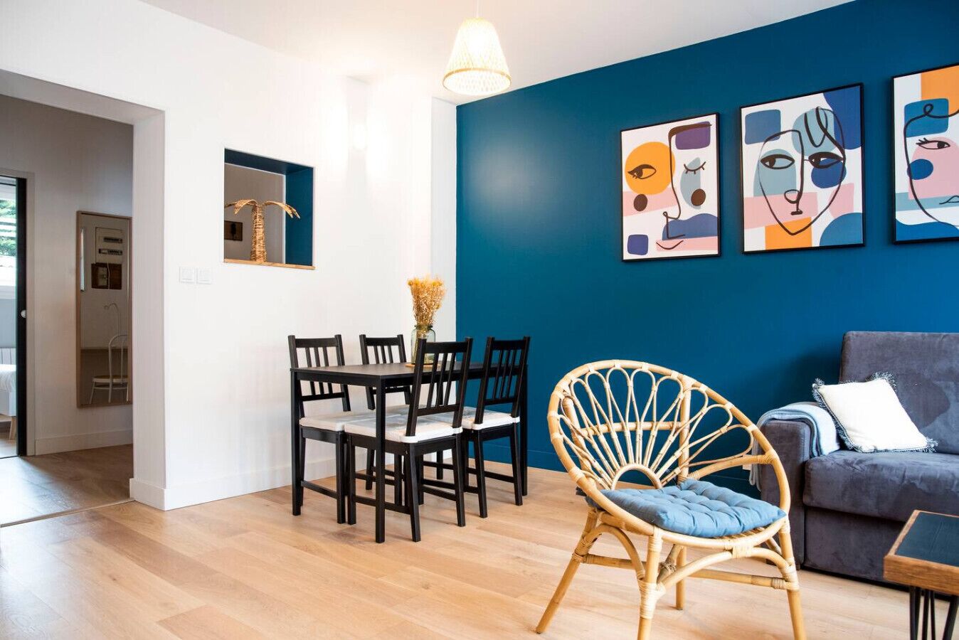 Un salon moderne comprenant un coin repas, un canapé et des œuvres d’art abstrait accrochées au mur.