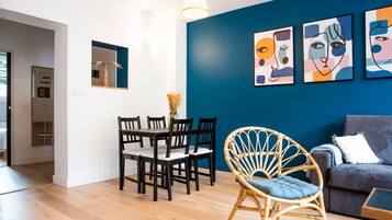 Un salon moderne comprenant un coin repas, un canapé et des œuvres d’art abstrait accrochées au mur.