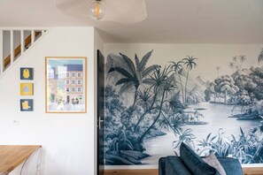 A room with a staircase, a mural of a river scene, and three framed pictures on the wall. - Mansion near downtown and the beach (Granville)