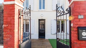 A red brick building with a black gate, a wooden pathway, and a black door with a window above it. - Mansion near downtown and the beach (Granville)