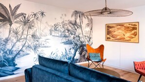 A room with a mural of a tropical landscape, a modern chair, and a framed picture on the wall. - Mansion near downtown and the beach (Granville)