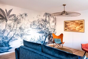 A room with a mural of a tropical landscape, a modern chair, and a framed picture on the wall. - Mansion near downtown and the beach (Granville)