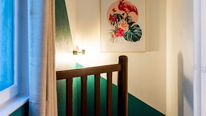 En trappa med ett träräcke, en väggmonterad lampa och ett inramat konstverk med tropiskt motiv.