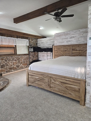 A bedroom with a bunk bed, a ceiling fan, stone wall, and a window with sheer curtains. - Cozy 2-bedroom apartment in Berlin. Ohio with AC (Millersburg)