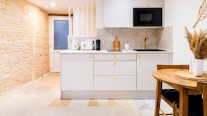 Una cocina moderna con armarios blancos, un microondas negro, un lavamanos y un comedor con una mesa y sillas de madera.