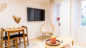 Un comedor con una mesa redonda, sillas, un televisor montado en la pared y una ventana con vistas.
