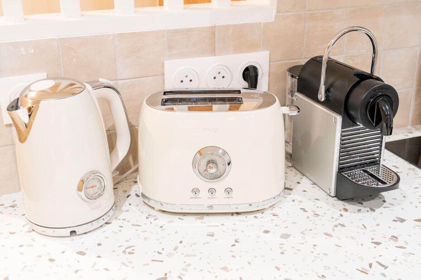 A kitchen with a white electric kettle, a white toaster, and a black coffee machine.