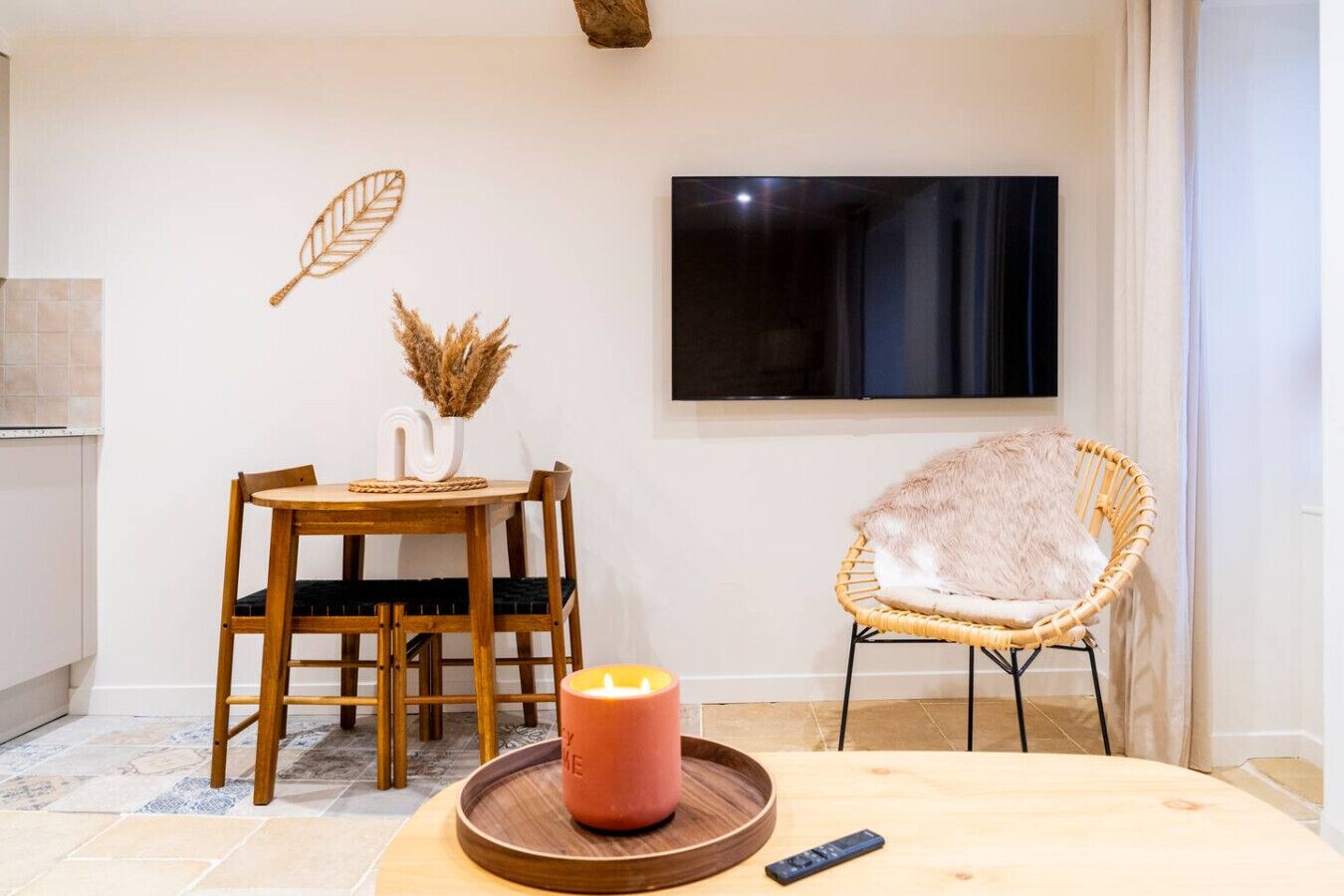 Un coin repas avec une table en bois, des chaises, une bougie et une télécommande.