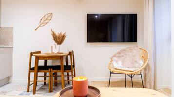 Un coin repas avec une table en bois, des chaises, une bougie et une télécommande.