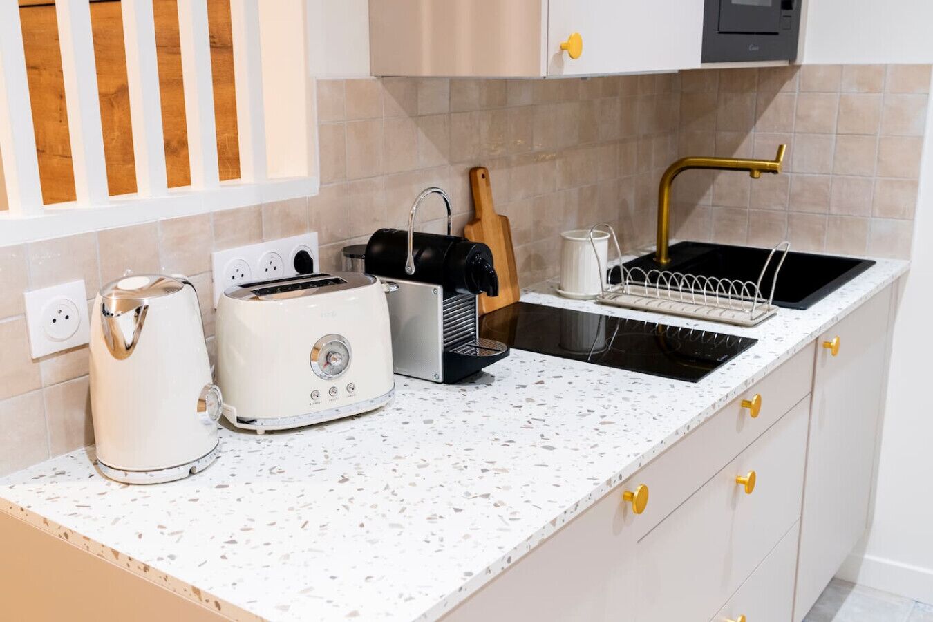 A kitchen with a countertop, a toaster, a kettle, a sink, and a knife block.