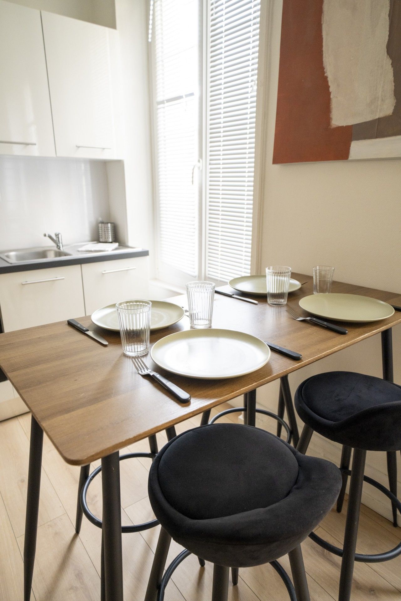 Een eetgedeelte met een houten tafel voor vier personen, compleet met borden, glazen en bestek.
