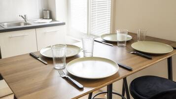 Een eetgedeelte met een houten tafel voor vier personen, compleet met borden, glazen en bestek.