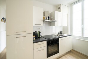 Een moderne keuken met witte kasten, een zwart aanrecht en een ingebouwde oven.