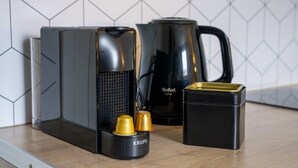 A kitchen with a coffee maker, a kettle, and a Krups coffee grinder on the counter. - Nice studio apartment for two, near the university (Caen)