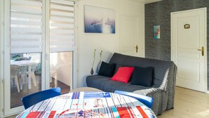 Ett rum med ett matbord, en soffa och en skjutdörr i glas som leder ut till ett utomhusområde.