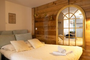 A room with a bed, pillows, a wooden wall, a mirror, and a lamp. - A Favorite Studio Right in the Heart of Downtown (Caen)