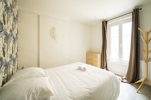 Un dormitorio con cama, cómoda, ventana con cortinas y decoración de plumas en la pared.
