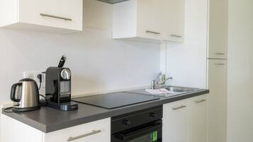 A modern kitchen with white cabinets, a black countertop, a built-in oven, and a patterned tile floor.