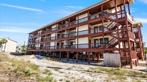 Un immeuble à plusieurs étages, doté de balcons et d’un escalier situé sur le côté droit.