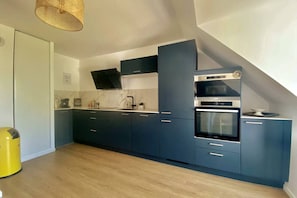 Una cocina moderna con armarios azul oscuro, horno empotrado y microondas.