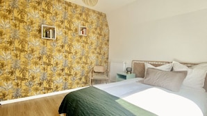 Una camera da letto con un letto, un comodino, un termosifone e una parete con un motivo tropicale.