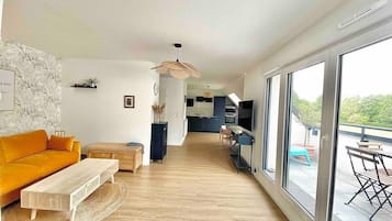 Un salon moderne comprenant un canapé, une table basse et un coin repas avec une table et des chaises.