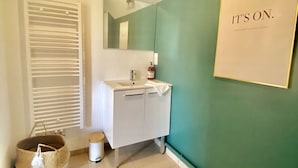 Un bagno con un mobile lavabo bianco, uno specchio, un asciugamano e un cestino.