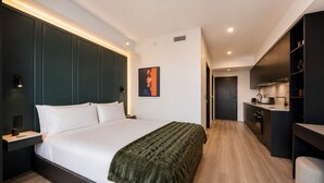 A modern hotel room with a large bed, a bedside table, a wardrobe, and a kitchenette. - Luxury Brand New Suite w/ Bay Views & Rooftop Pool (Miami)