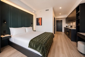 A modern hotel room with a large bed, a bedside table, a wardrobe, and a kitchenette. - Luxury Brand New Suite w/ Bay Views & Rooftop Pool (Miami)